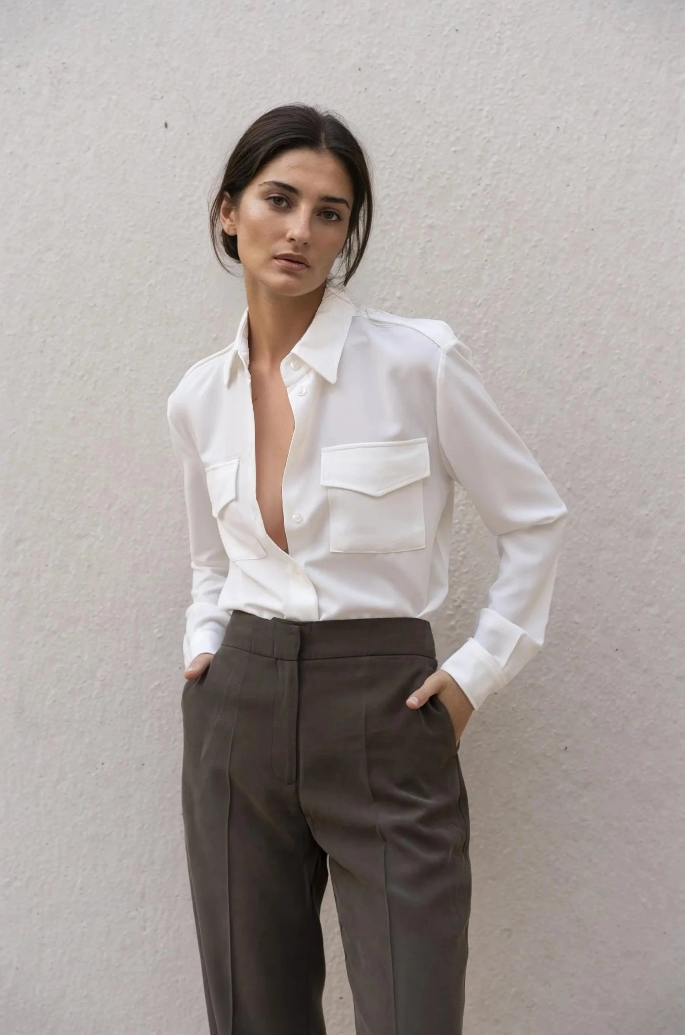 Femme portant une chemise blanche en soie avec poches et pantalon marron foncé