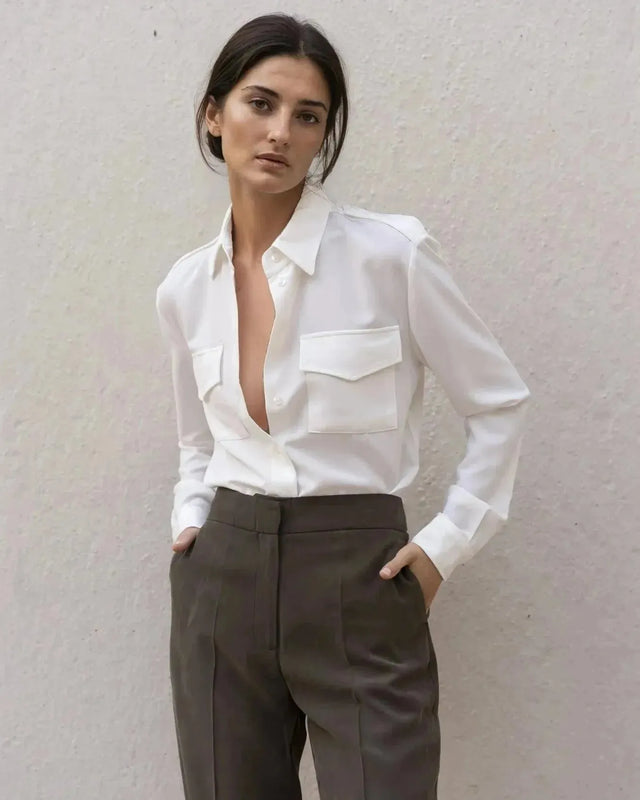 Chemise blanche en soie à poches pour femme, portée avec élégance, associée à un pantalon chic, parfaite pour un look moderne.