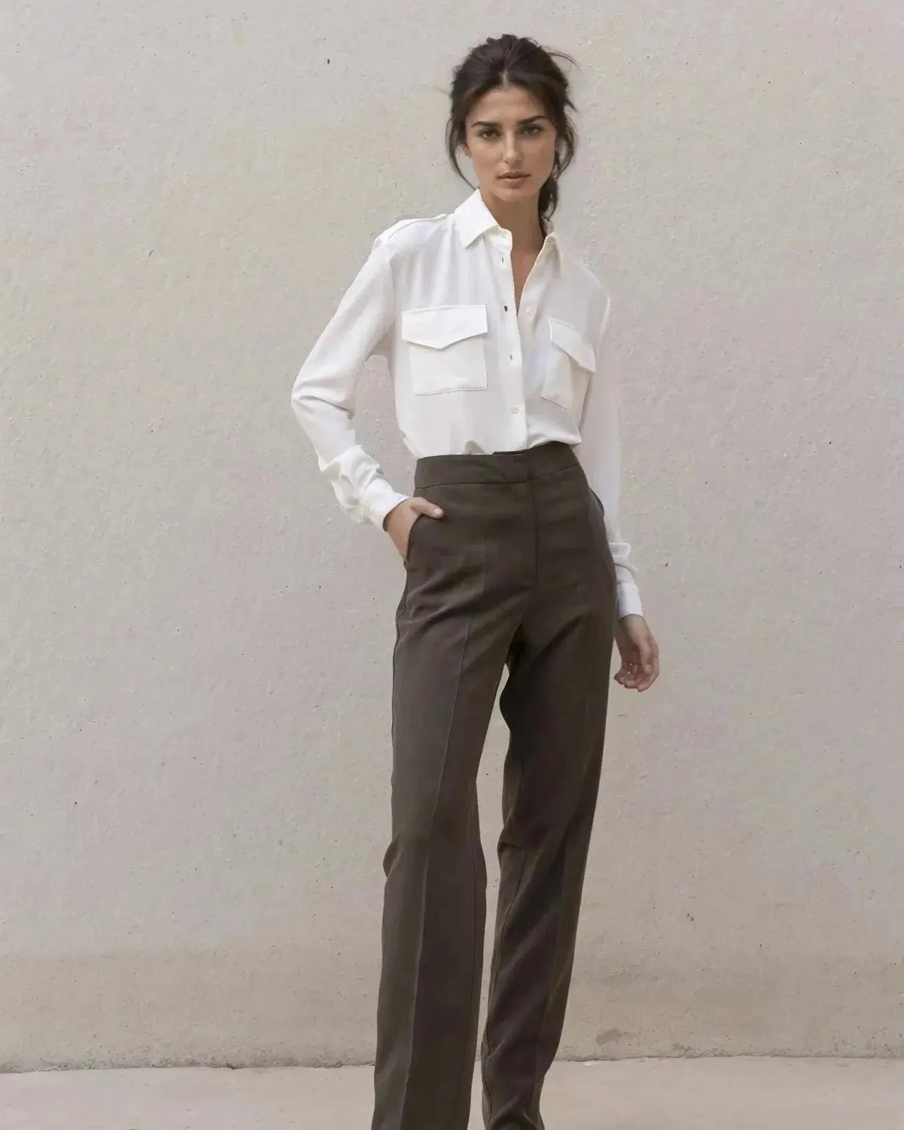 Modèle féminin portant une chemise blanche en soie à poches avec un pantalon élégant, parfaite pour un look de jour ou de soirée.