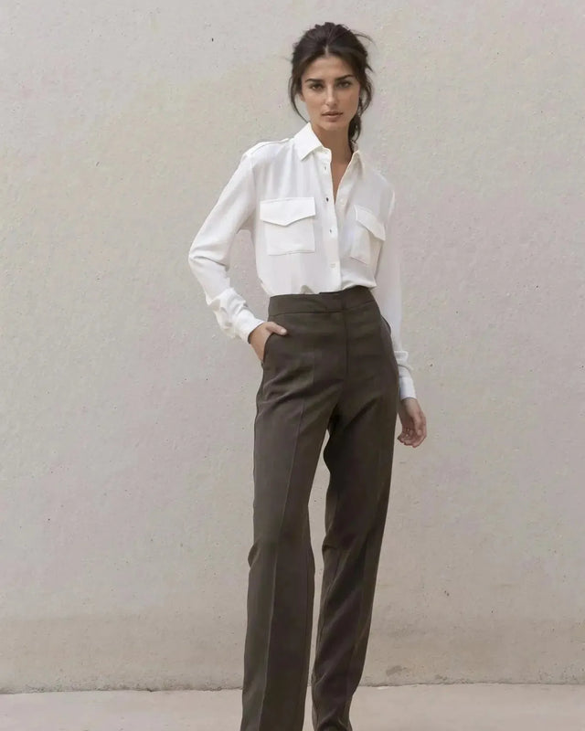 Modèle féminin portant une chemise blanche en soie à poches avec un pantalon élégant, parfaite pour un look de jour ou de soirée.