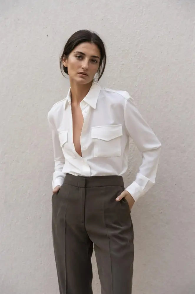 Femme portant une chemise blanche en soie avec poches et pantalon marron foncé