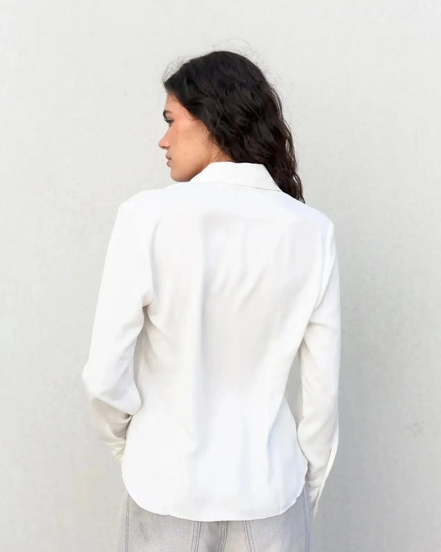Détails de la chemise blanche femme grand col ajustée à pinces, mettant en avant sa coupe stylée.