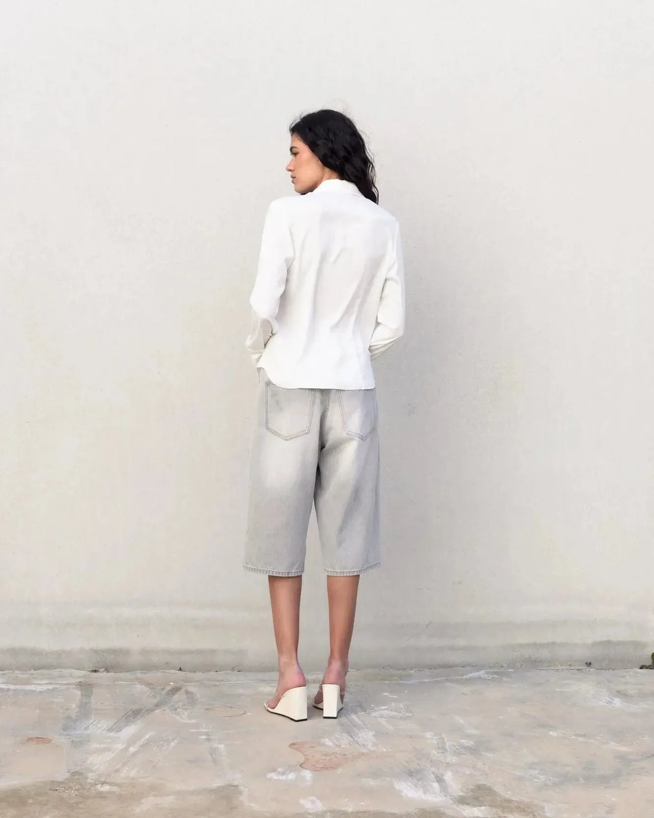 Vue arrière d'une chemise blanche femme grand col ajustée à pinces sur une model, style chic.