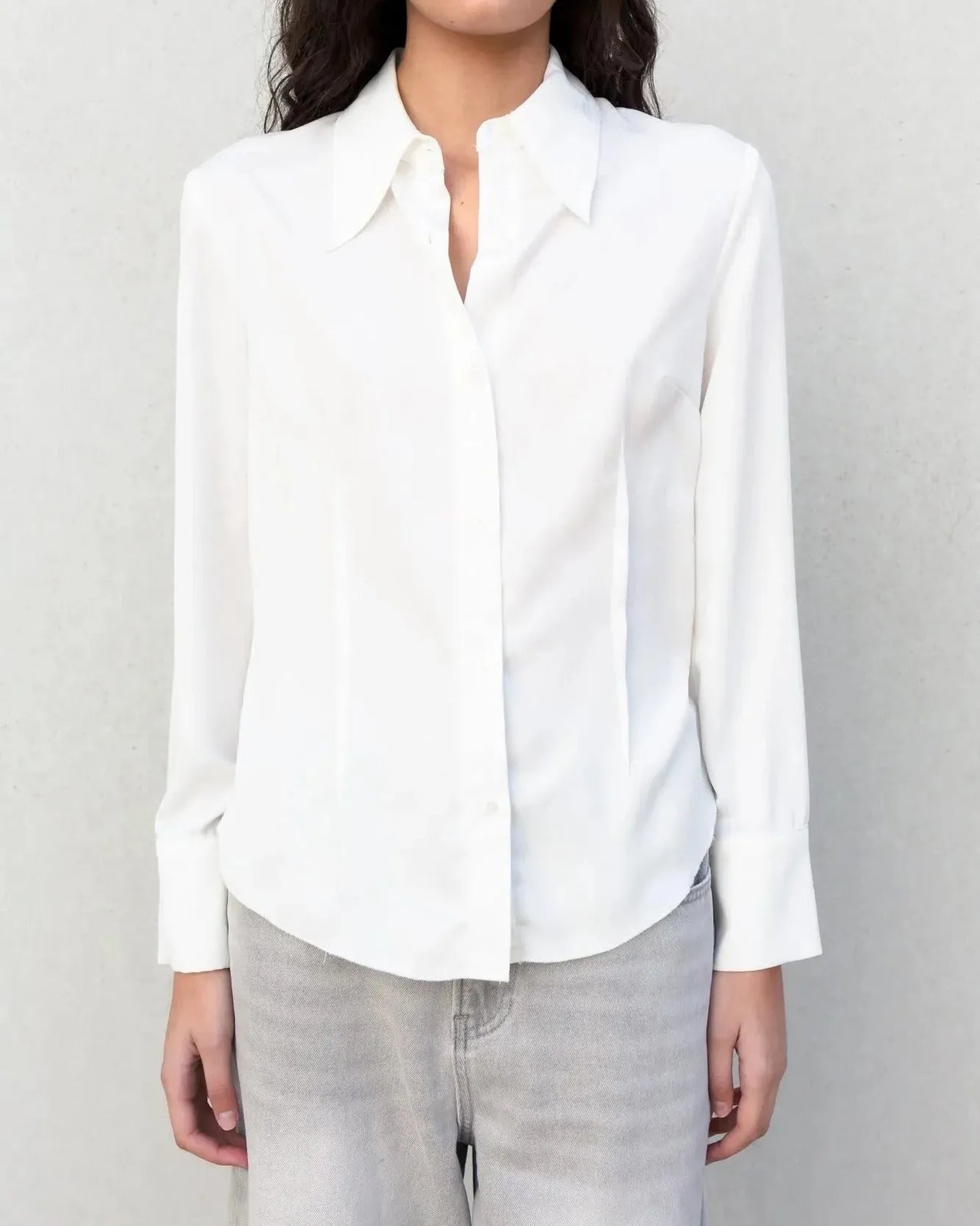 Vue rapprochée d'une chemise blanche femme grand col ajustée à pinces, parfaite pour le bureau.