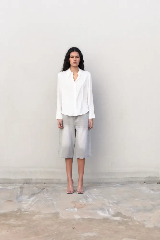Femme portant une chemise blanche ajustée à pinces avec shorts gris et sandales à talons