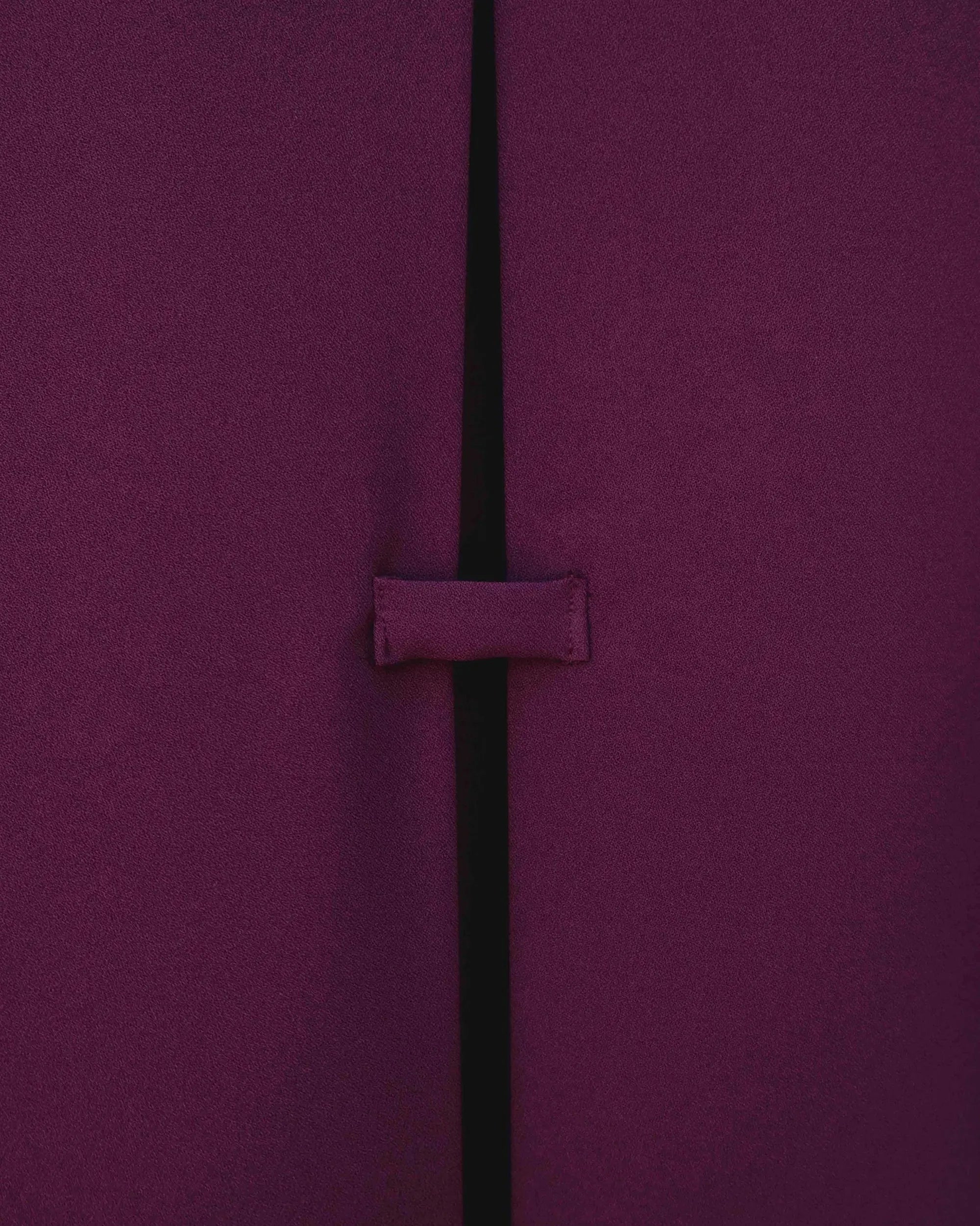 Détail de la fente à l'arrière de la chemise élégante bordeaux à boutons dorés pour femme, soulignant son design raffiné. Une excellente option pour une chemise bordeaux femme élégante.