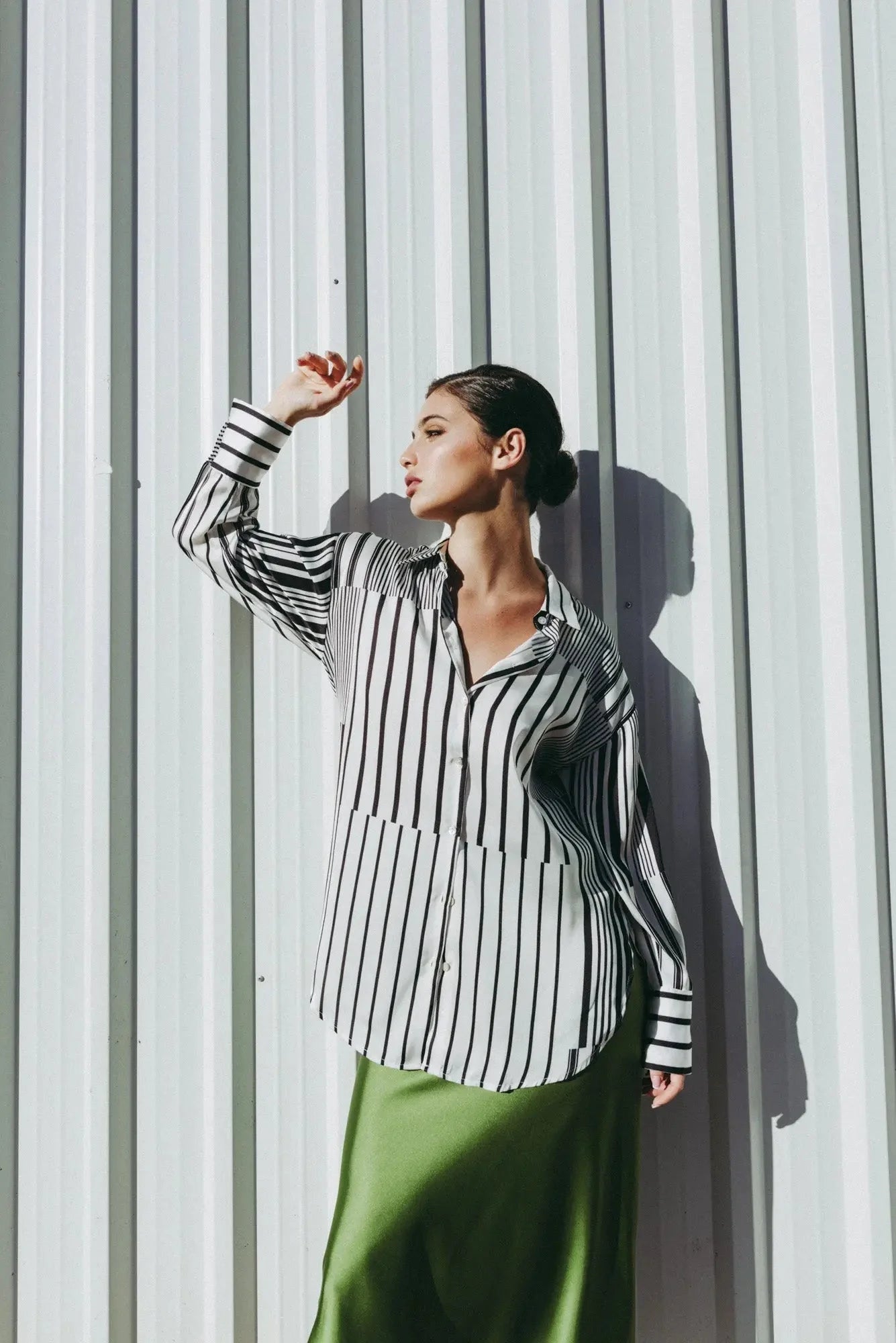 Femme portant une chemise imprimée rayures et une longue jupe satin olive verte
