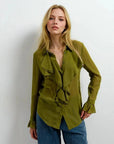 Chemise Femme à Volants Chic Vert Olive, un chemisier à volants femme mis en avant par un modèle avec un sourire, montrant les détails raffinés du vêtement.