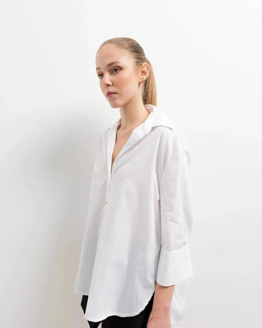 Chemise Femme Blanche Ample en popeline, style décontracté, portée par un modèle en studio avec un fond neutre.