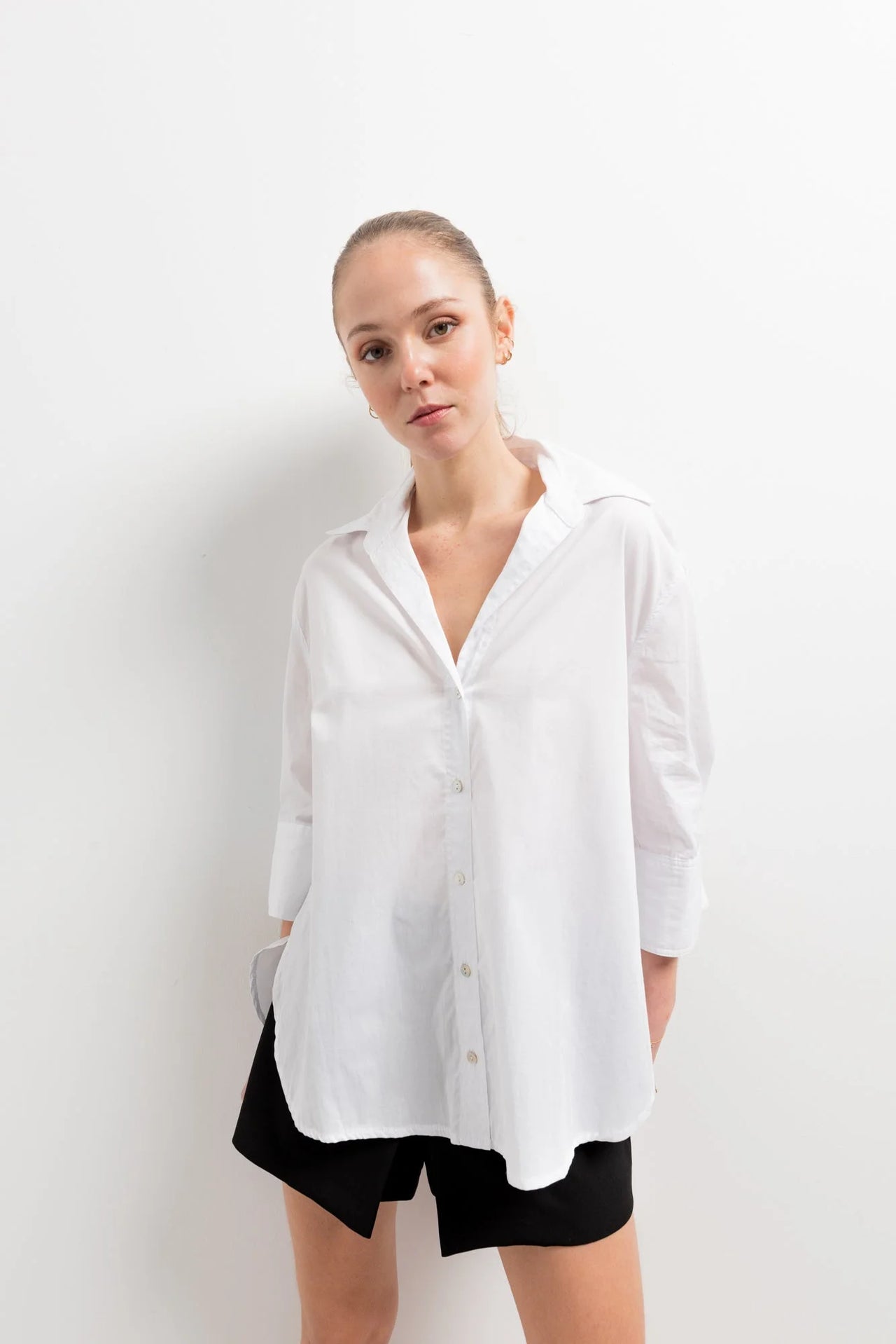 Chemise Femme Blanche Ample en popeline, avec un modèle posant en studio, mettant en avant le design chic.