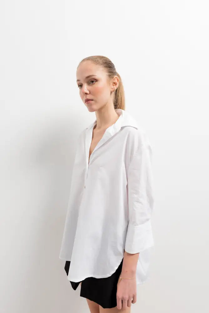 Chemise femme blanche ample portée par une femme en chemise oversize et shorts noirs