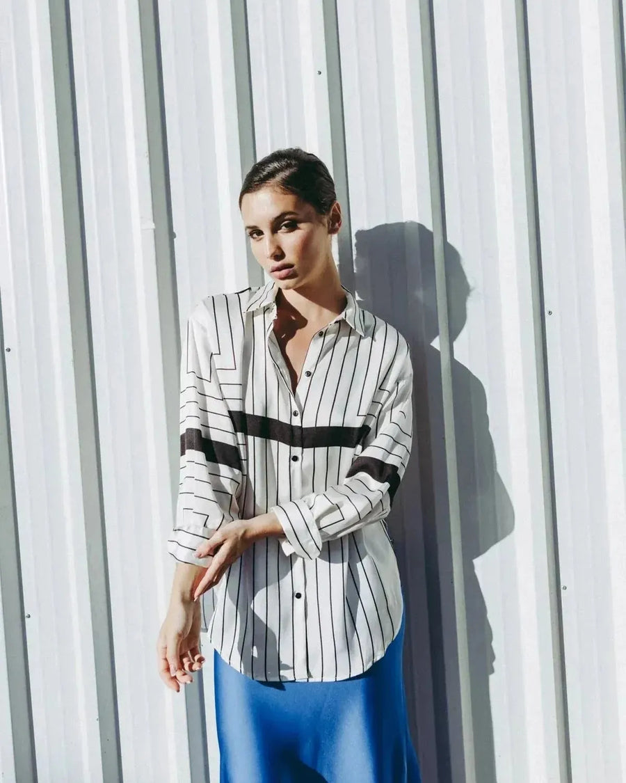 Chemise Femme Imprimée à Rayures Noires portée par une femme, ajoutant une touche chic avec sa coupe ample fluide, idéale pour un look décontracté.