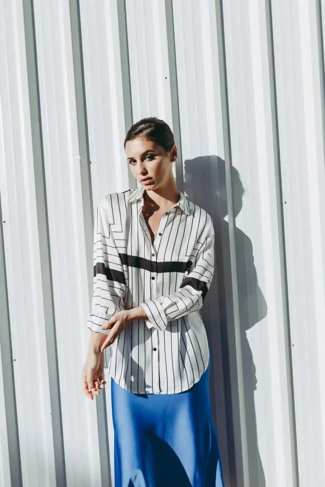 Femme portant une chemise imprimée à rayures noires et une jupe satinée bleue