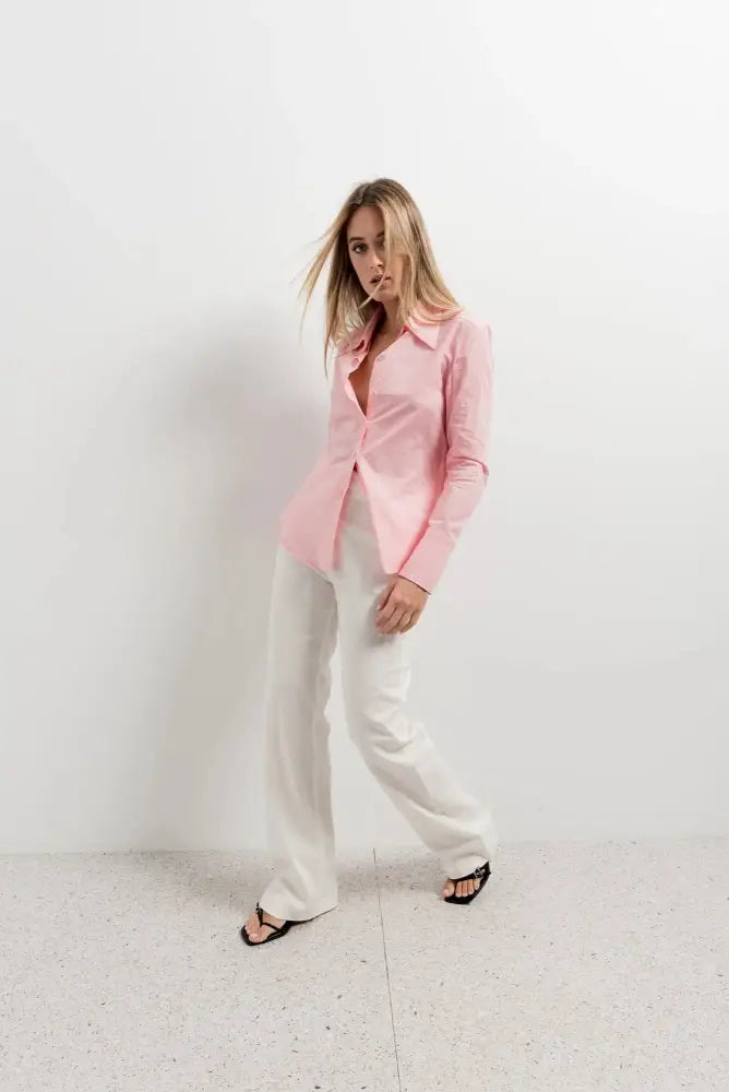 Femme portant chemise flanelle rose clair et pantalon blanc large-leg, look tendance
