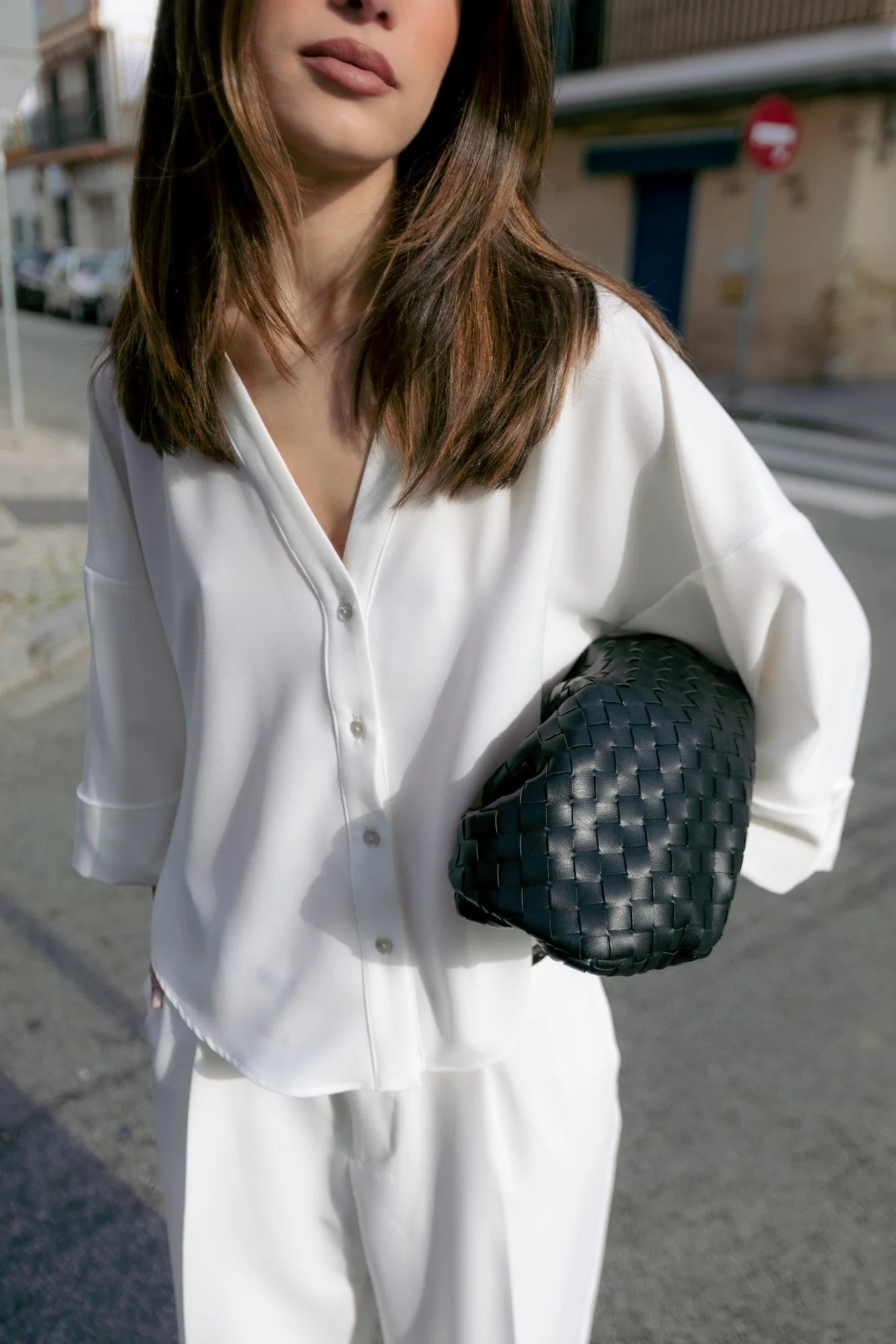 Sac clutch en cuir noir associé à la chemise fluide blanche à manches larges