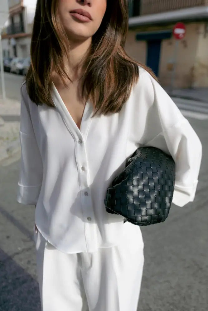 Sac clutch en cuir noir associé à la chemise fluide blanche à manches larges