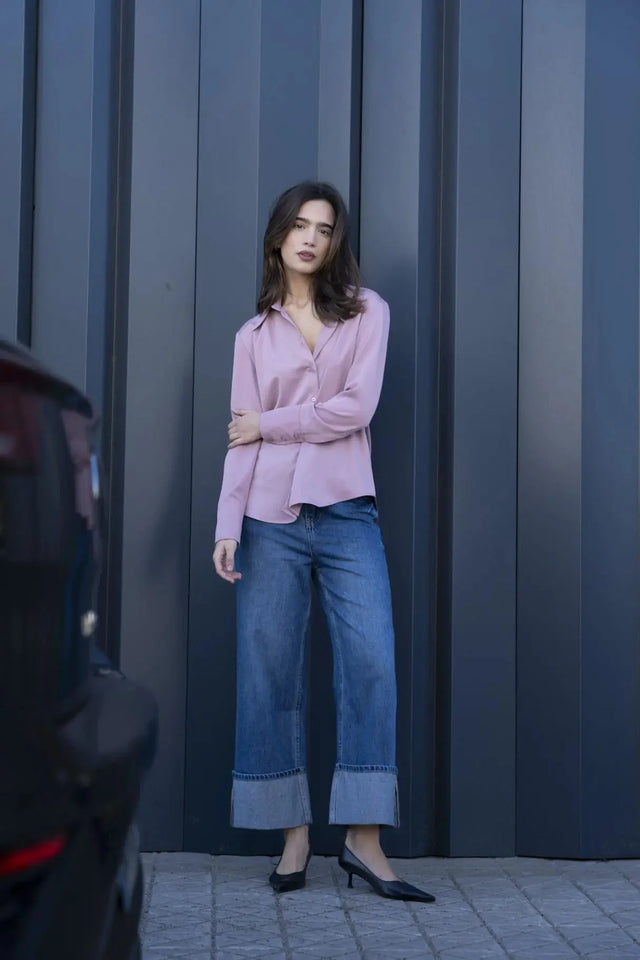 Modèle posant avec la chemise fluide femme lilas à col pointu, associée à un pantalon denim pour une allure moderne.