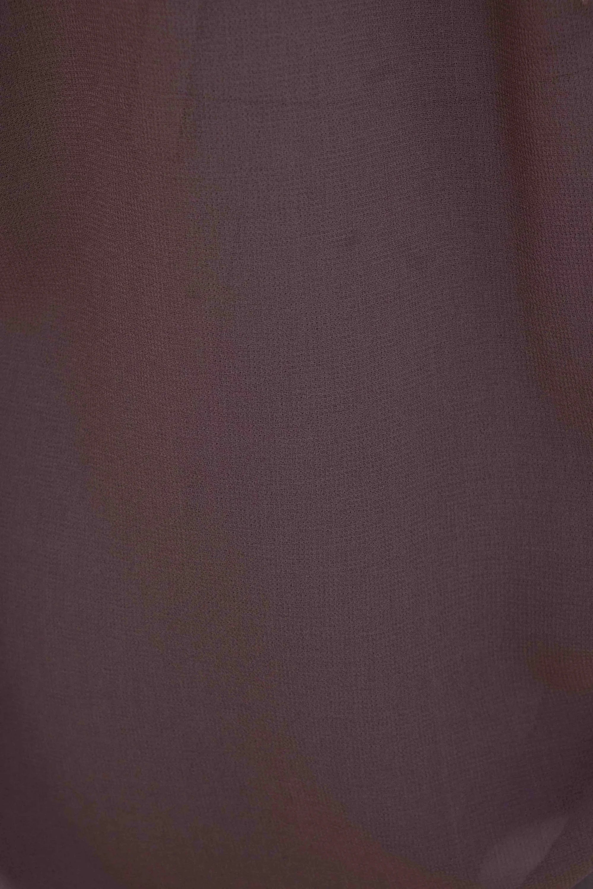Détail du tissu d'une chemise col lavallière fluide marron transparent, illustrant la légèreté et la transparence du matériau.