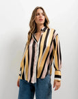 Femme portant une chemise imprimée animal à rayures diagonales, style moderne avec rayures jaune et noir, idéale pour un look tendance. Chemise rayure femme.