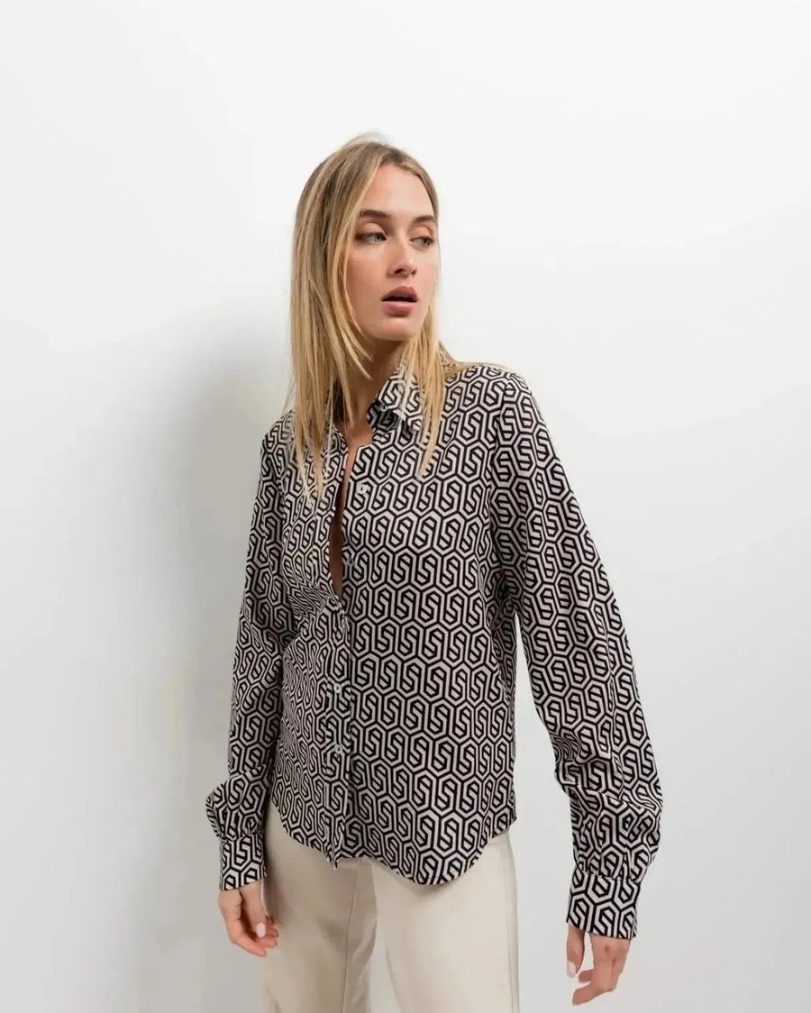 Femme portant une chemise noir et blanc imprimée animal au design unique, accentuant son allure élégante et moderne.