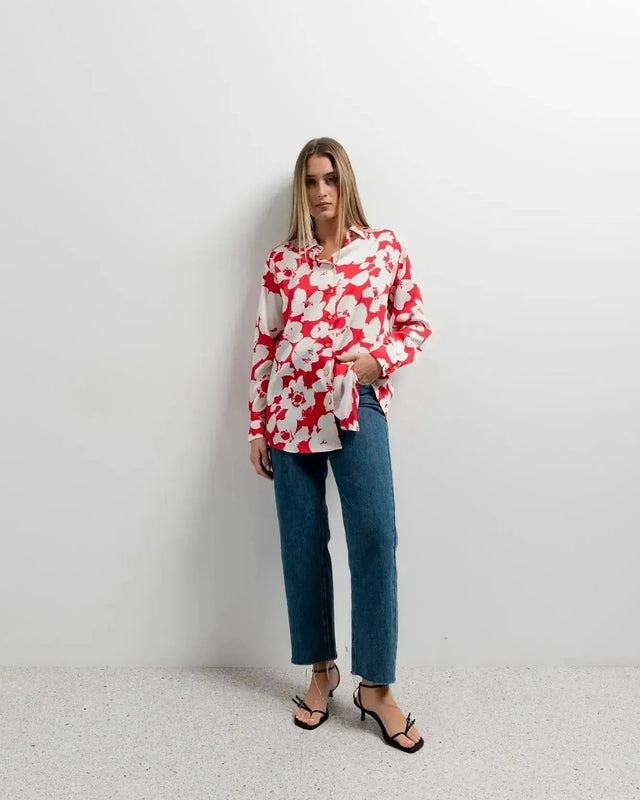Mode féminine avec chemise fleurie femme rouge et blanche en satin, portée avec un jean décontracté pour un look élégant et confortable.