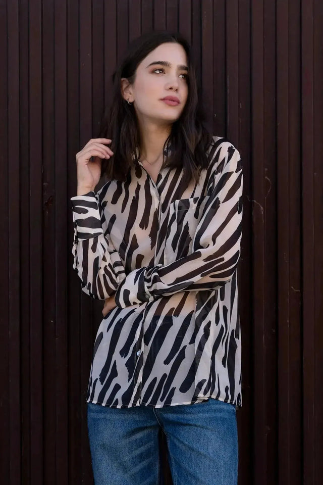 Chemise Transparente Femme Motif Zèbre Noir et Beige, Fluide et Élégante, montrée sur un modèle dans un environnement extérieur, reflétant un style casual.