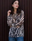 Chemise Transparente Femme Motif Zèbre Noir et Beige, Fluide et Élégante, montrée sur un modèle dans un environnement extérieur, reflétant un style casual.