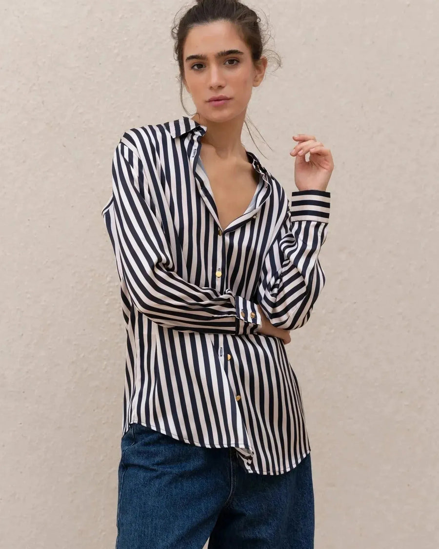 Femme posant avec les bras croisés, vêtue d'une chemise rayée bleu marine et blanc, soulignant le style moderne et structuré, à découvrir avec la chemise rayée femme.