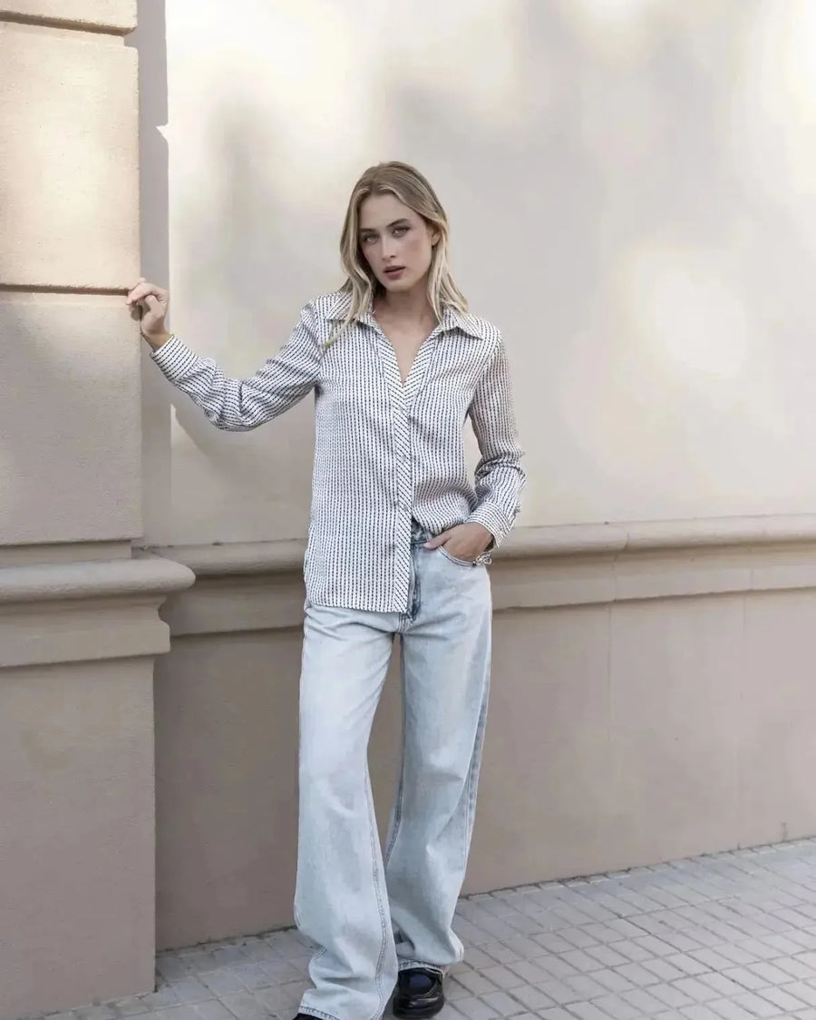 Femme posant avec confiance dans une chemise satin rayée, illustrant un look casual-chic avec la chemise en satin femme.