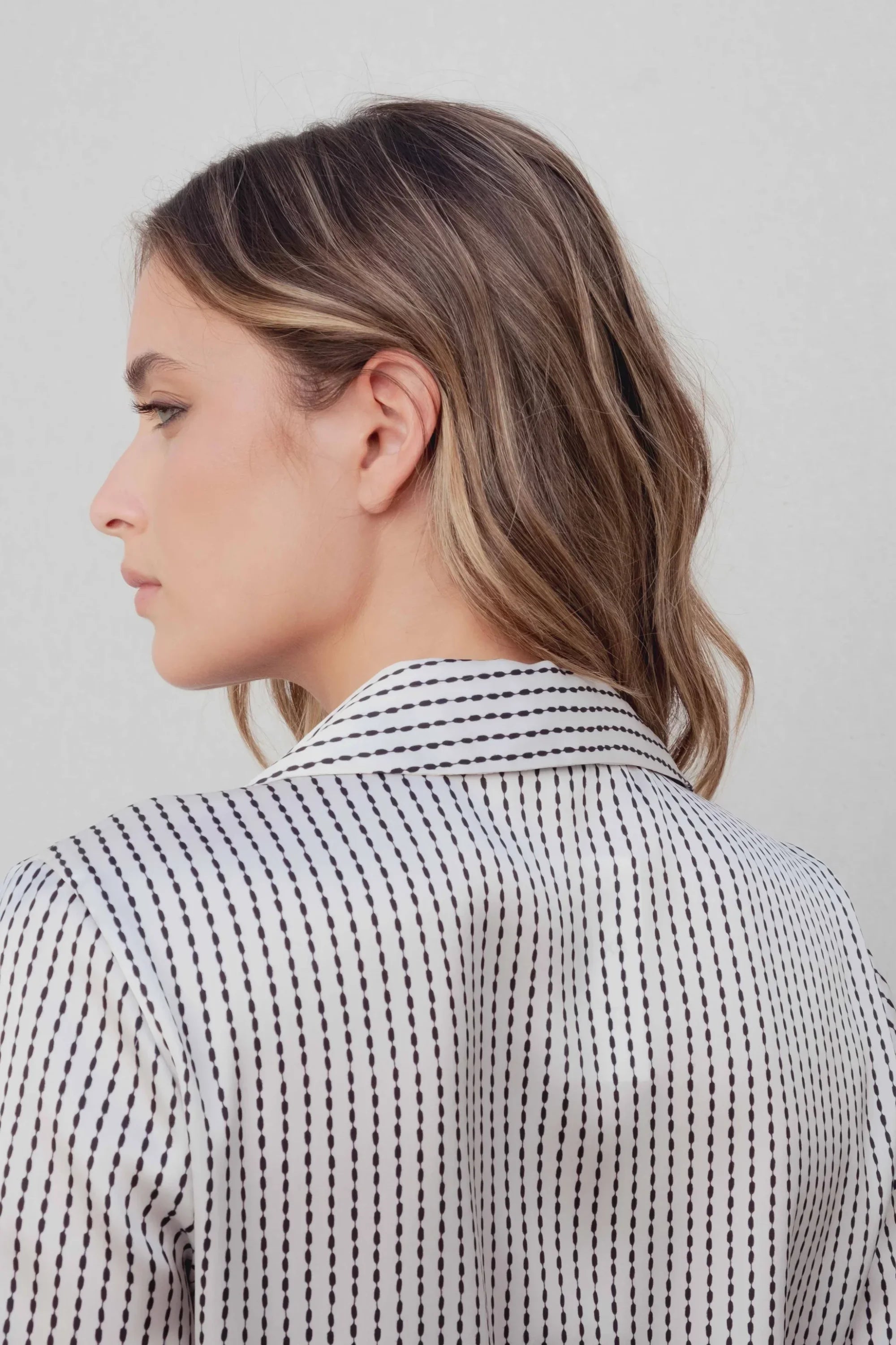 Femme portant une chemise satinée rayée pour une tenue casual élégance intemporelle