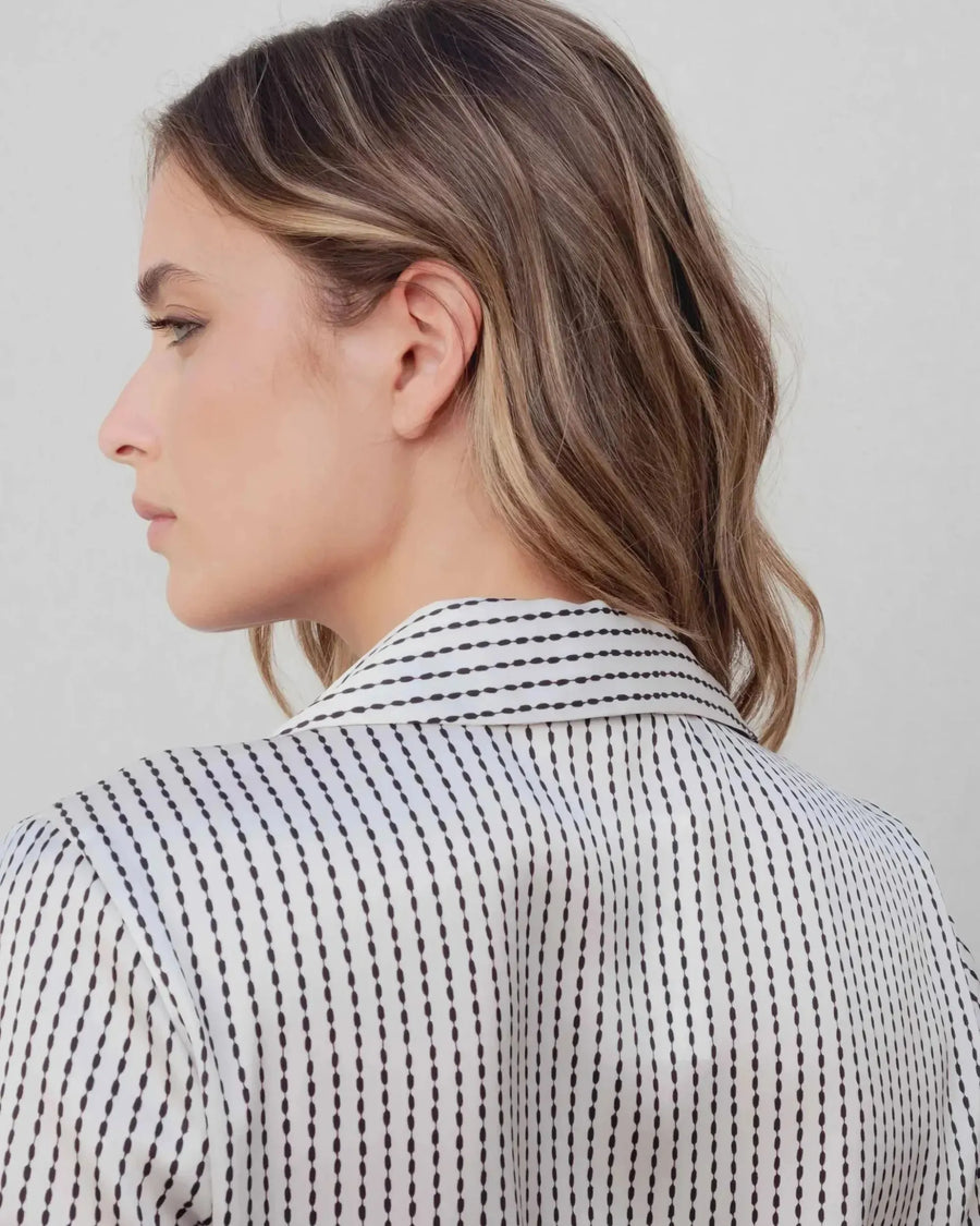 Vue de dos d'une femme en chemise satin rayée, soulignant la coupe féminine de cette chemise en satin femme.
