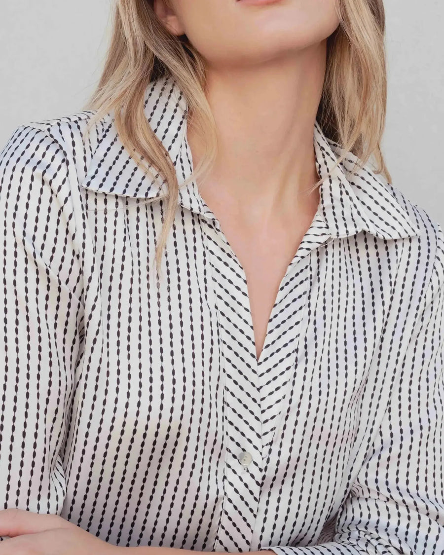 Zoom sur une chemise satin rayée portée par une femme, illustrant l'élégance intemporelle de la chemise en satin femme.