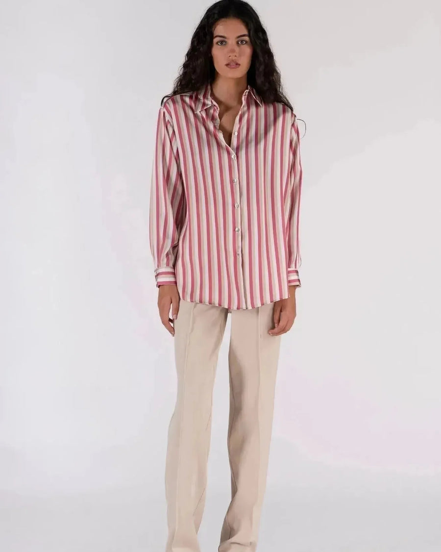 Chemisier satin femme chic à rayures verticales, couleur rose et beige, porté avec un pantalon beige pour un look sophistiqué, mannequin élégant en studio.