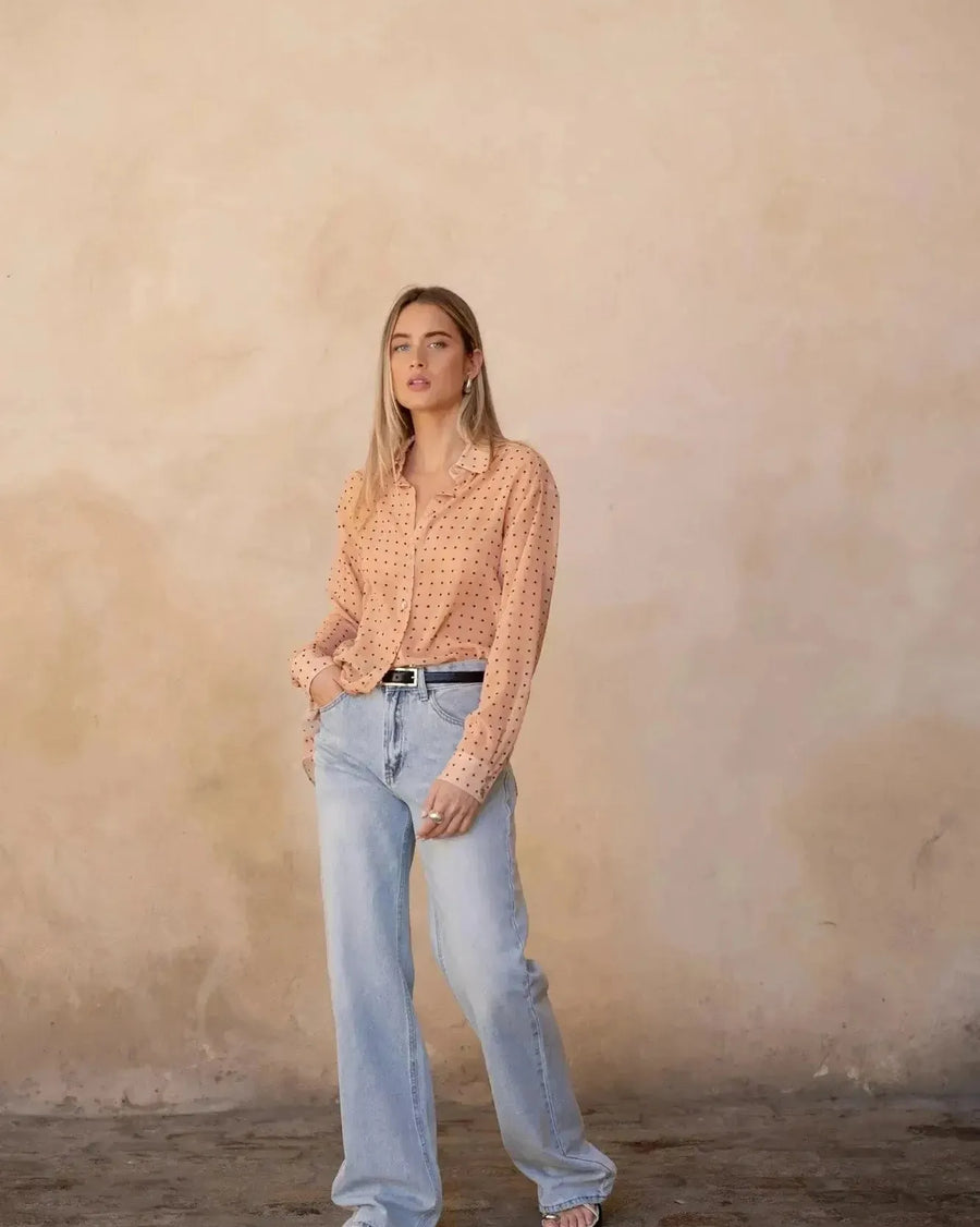 Chemise Transparente Femme À Pois Noirs – Blouse chic photographiée à l'intérieur, portée avec un jean pour un look décontracté.