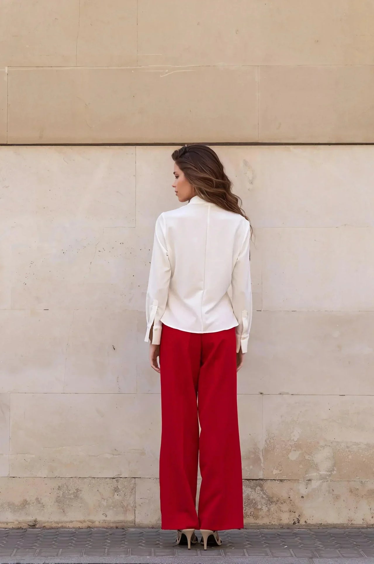 Vue arrière d'une femme dans une chemise élégante à plis et un pantalon rouge, parfait pour un look chic et contemporain.