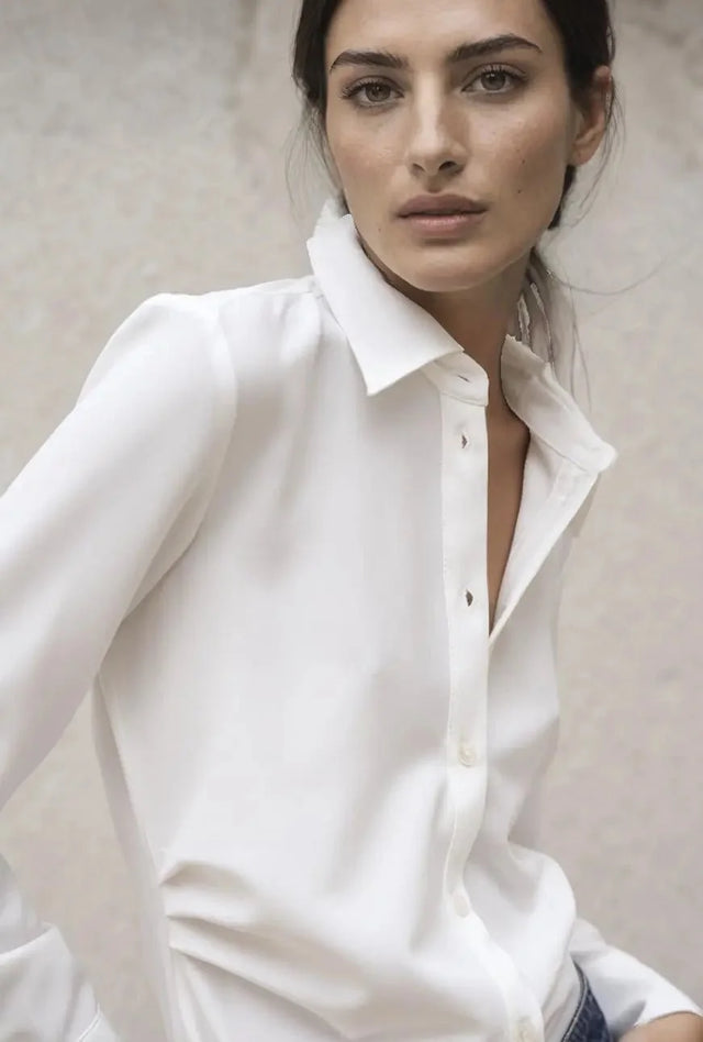 Gros plan sur le visage d'une femme portant une chemise élégante à plis, soulignant le tissu confortable et la qualité du design.