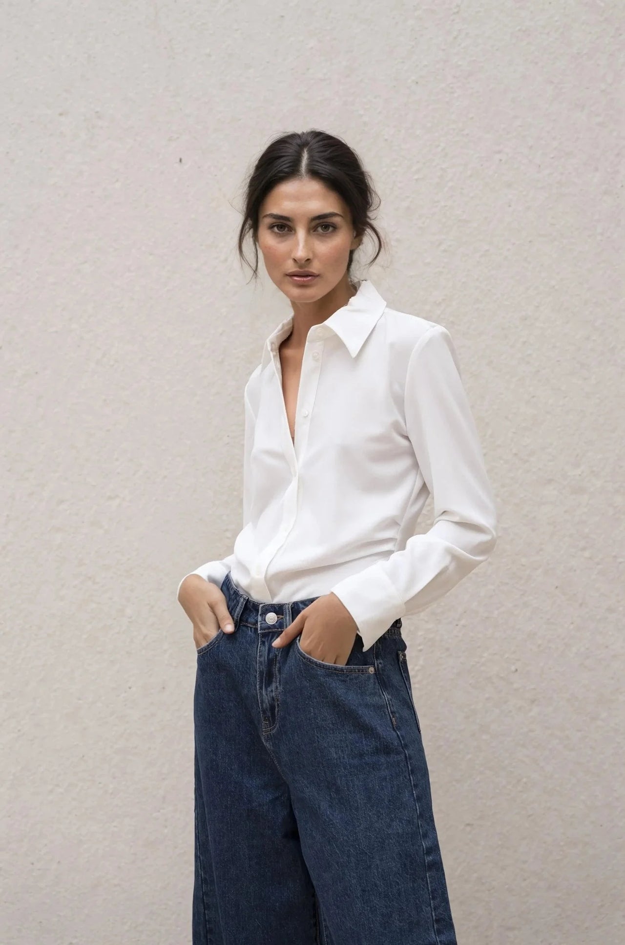 Une femme portant une chemise élégante à plis, vêtue d'un tissu confortable, style décontracté avec un jean large.