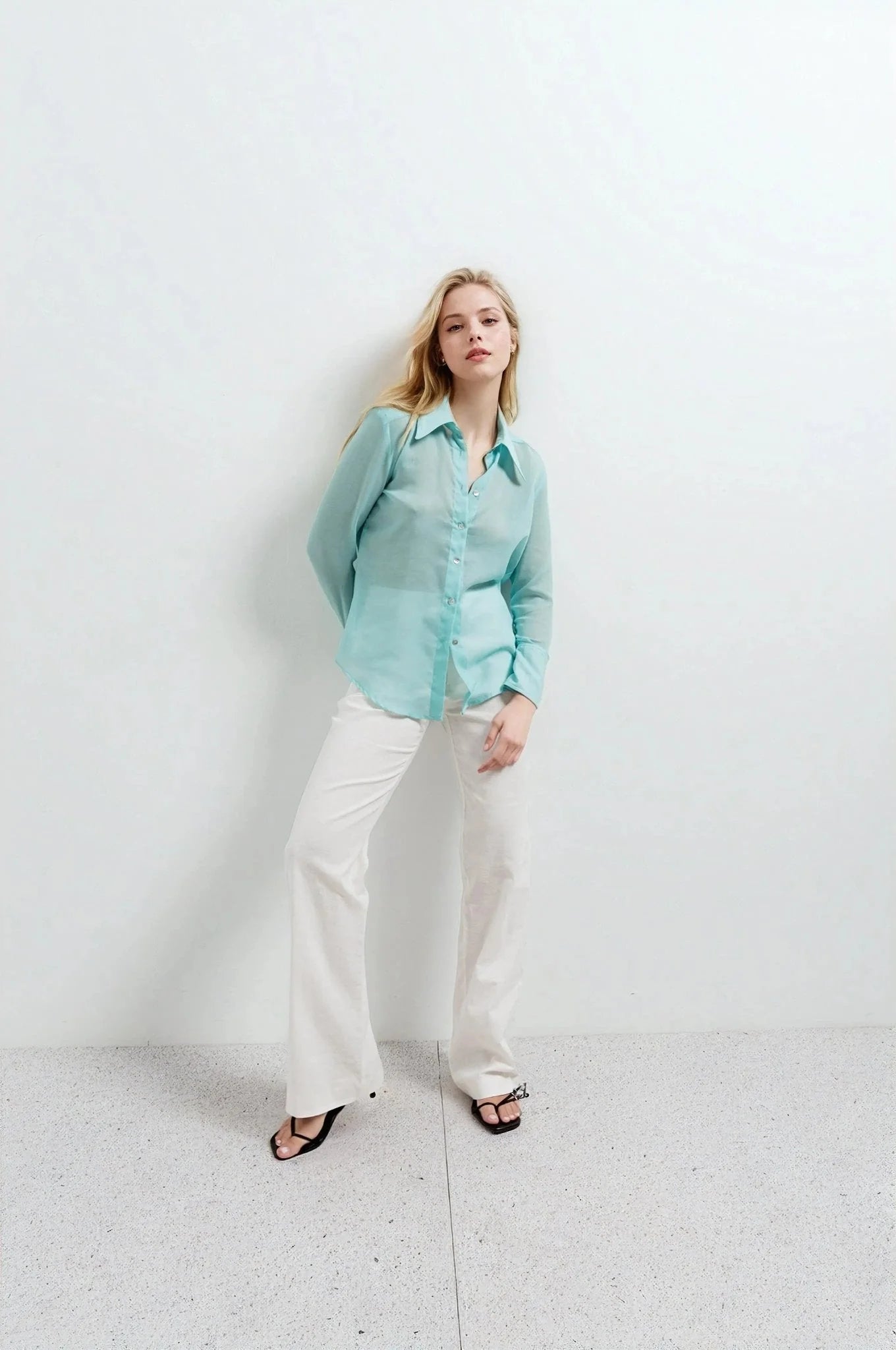 Femme en chemise transparente pour femme bleu aquatique, associée à un pantalon blanc, parfaite pour un look décontracté.