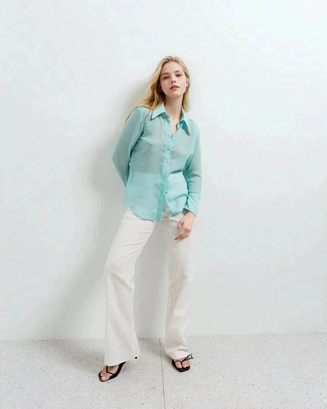 Femme en chemise transparente pour femme bleu aquatique, associée à un pantalon blanc, parfaite pour un look décontracté.