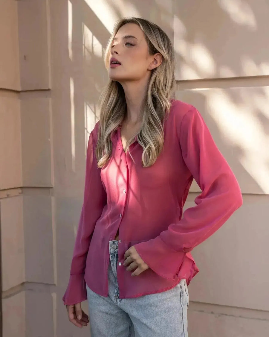 Femme dans une chemise transparente rose à manches longues pour femme, affichant un style élégant et contemporain. Idéale pour un look alliant confort et sophistication, notamment avec une chemise transparente femme.