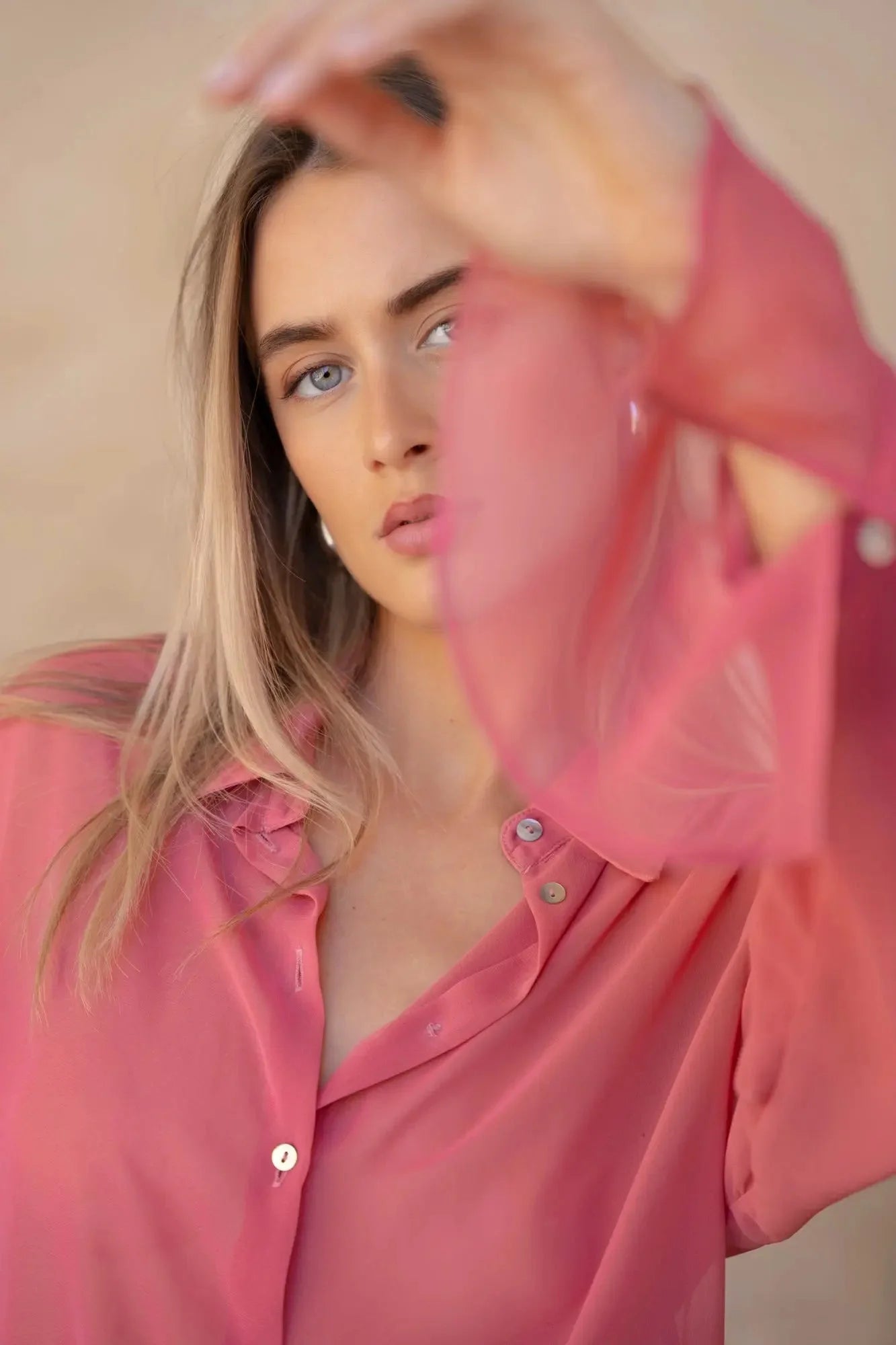 Femme portant une chemise transparente rose à manches longues, look élégant et féminin