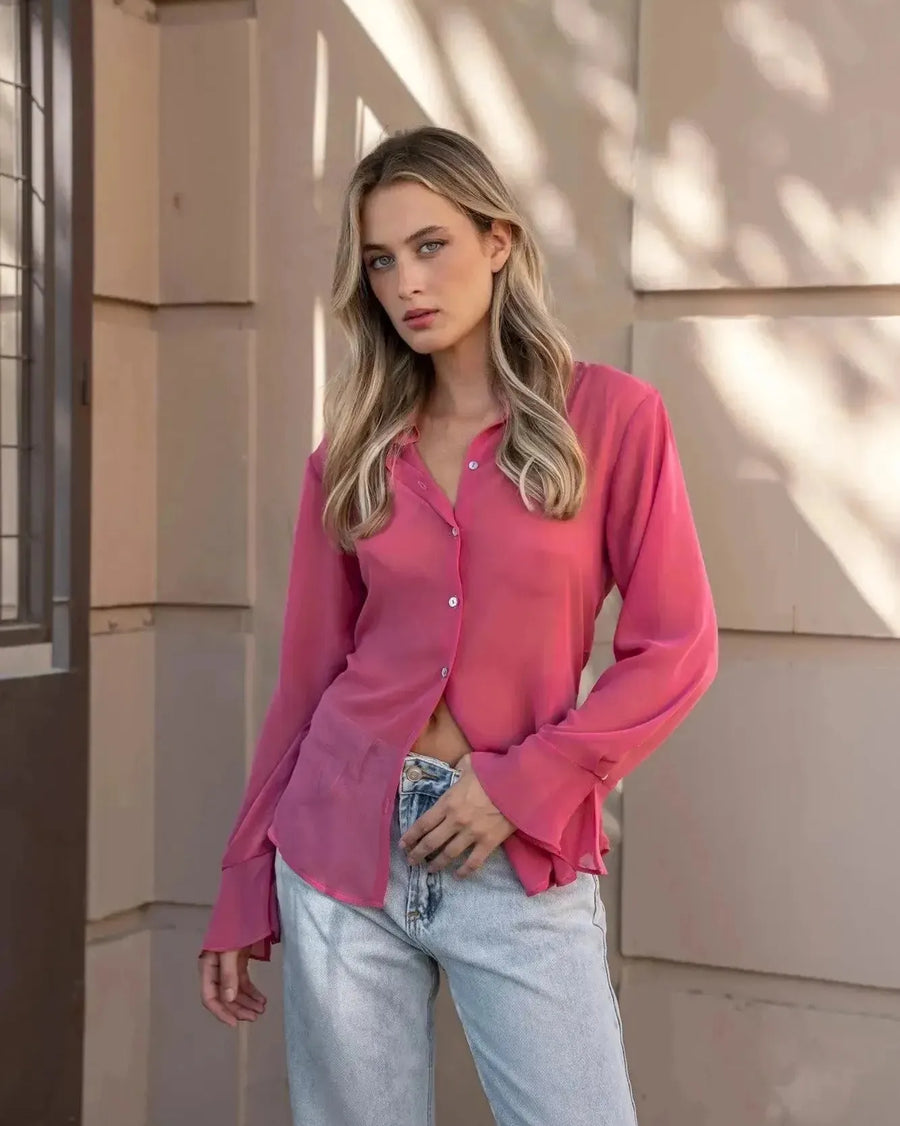 Femme portant une chemise transparente rose à manches longues pour femme, avec un look décontracté et moderne. Parfaite pour un style chic avec la chemise transparente femme.