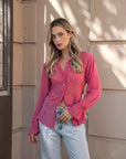 Femme portant une chemise transparente rose à manches longues pour femme, avec un look décontracté et moderne. Parfaite pour un style chic avec la chemise transparente femme.