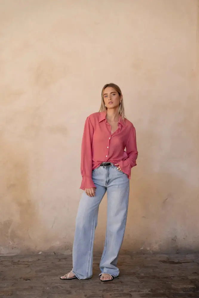 Femme portant une chemise transparente rose à manches longues avec jeans large et sandales blanches