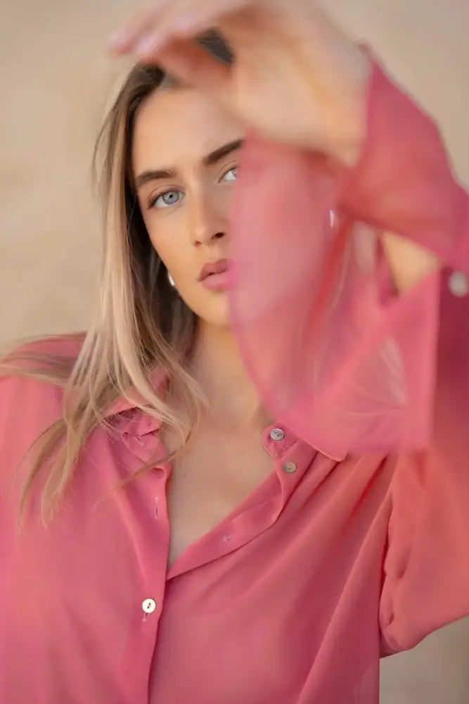 Femme portant une chemise transparente rose à manches longues, look élégant et féminin