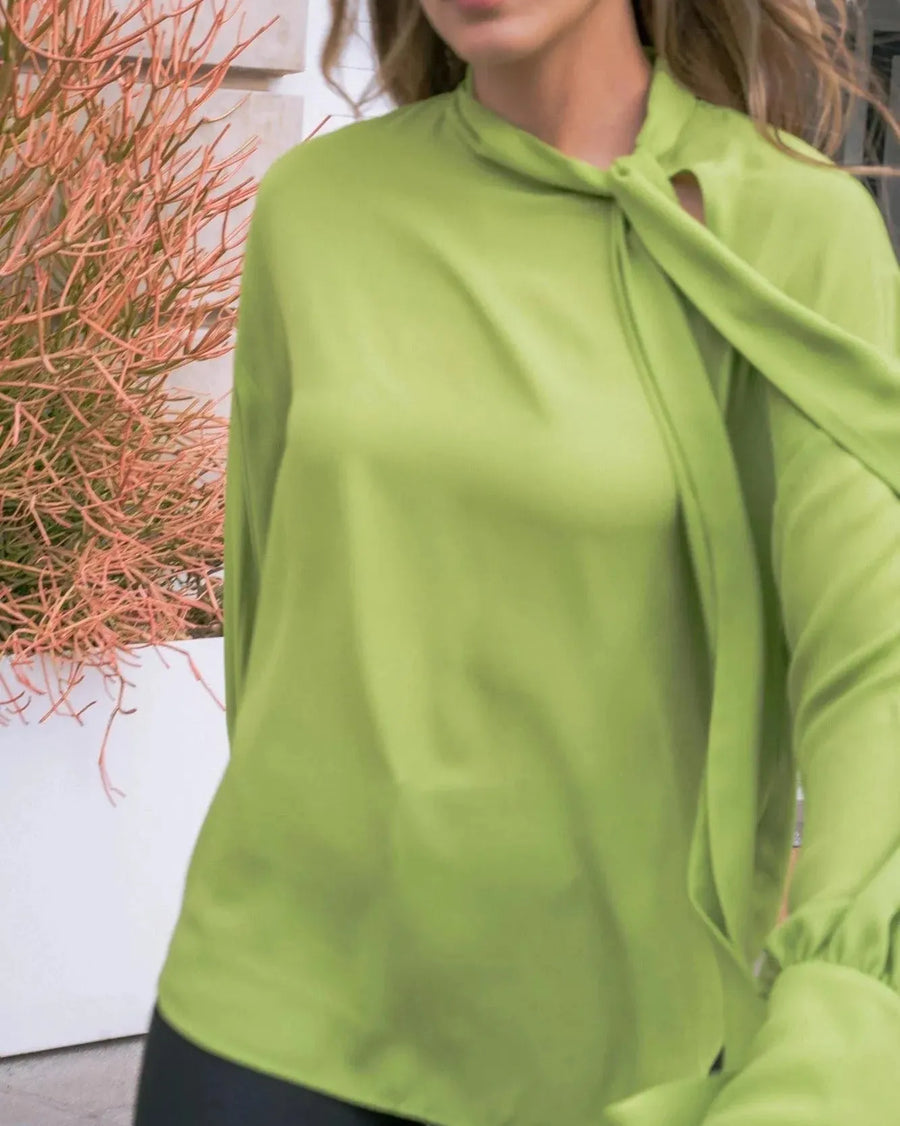 Chemise Verte Élégante Femme à Col Cravate, portant par une modèle dans un cadre moderne, mettant en avant son tissu fluide et son nœud chic. Idéale pour le style quotidien avec un look décontracté. Parfaite comme chemise col lavallière femme.