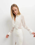 Femme portant une chemise à volants élégante en blanc, chic et polyvalente, avec un design délicat, parfaite pour diverses occasions.