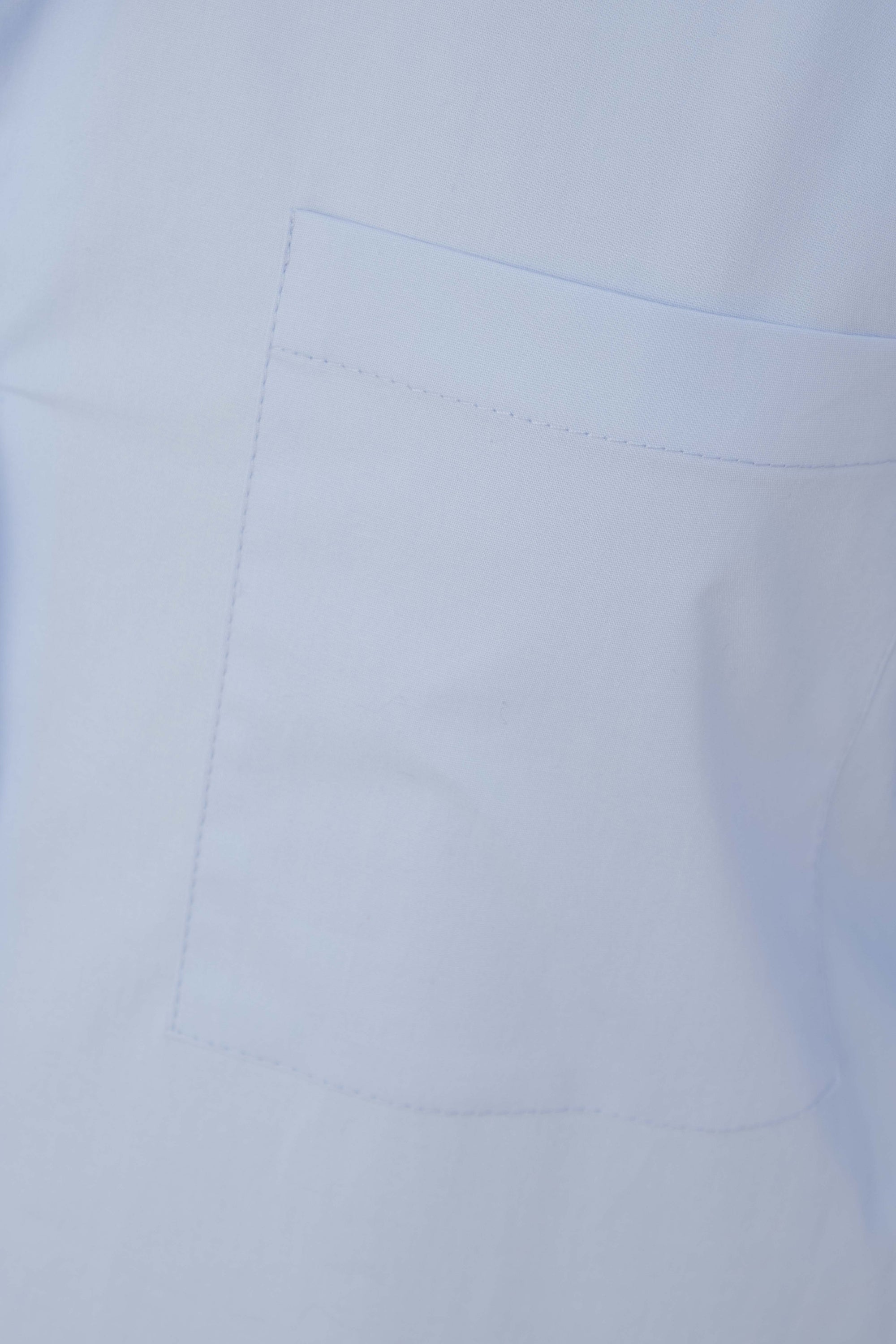 Détail d'une chemise oversize popeline bleu ciel femme, montrant la poche poitrine plaquée qui ajoute une touche fonctionnelle à cette pièce tendance.