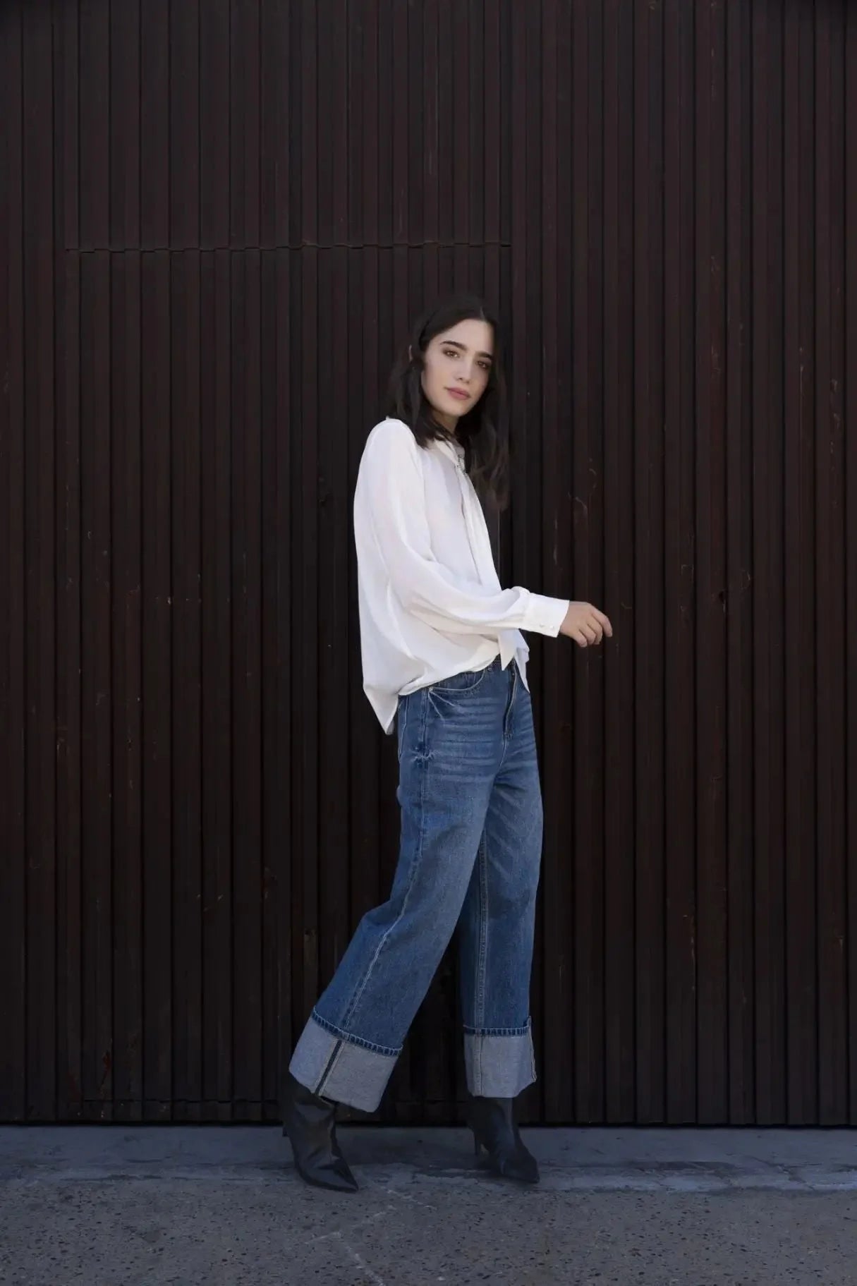 Femme portant un chemisier blanc à col papillon, jeans wide-leg et bottines noires