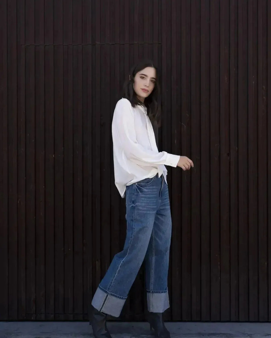 Femme portant un chemisier blanc à col papillon, jeans wide-leg et bottines noires